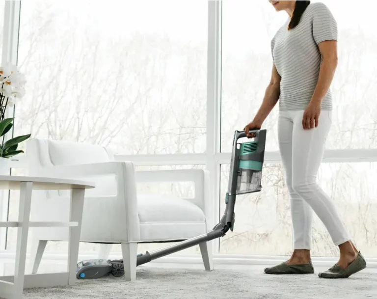 A woman vacuuming under a chair
