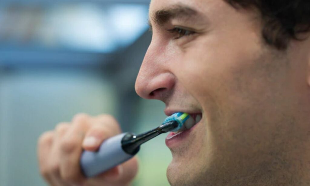 A man using a Sonicare, with the proper brushing angle